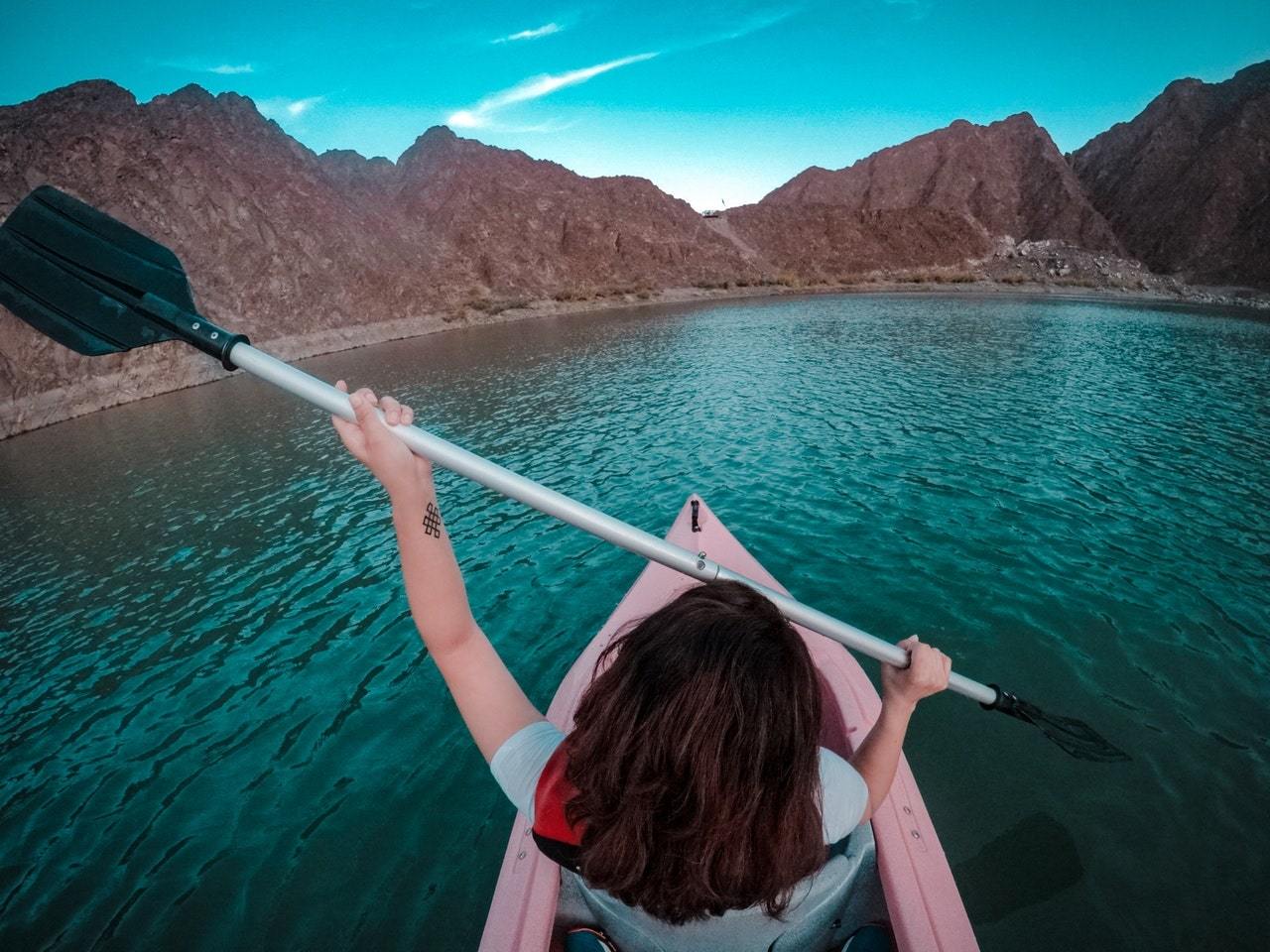Woman using paddle and kayak on lake